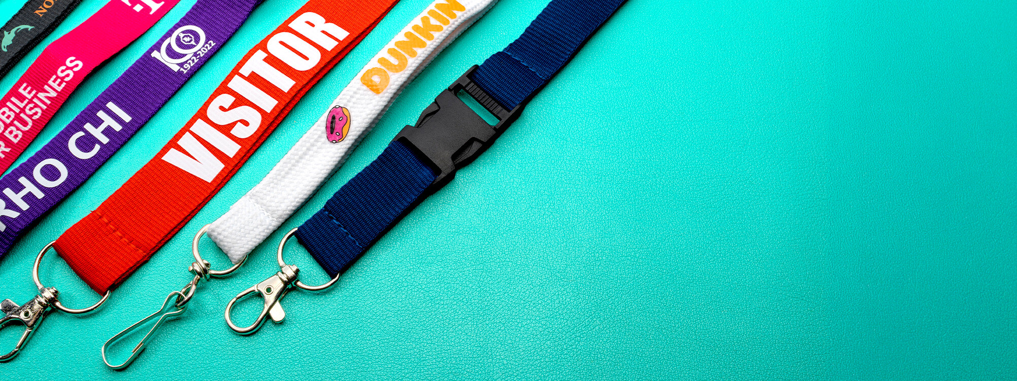 Colorful custom lanyards including Visitor, Dunkin, T-Mobile, and Rho Chi designs with various attachments